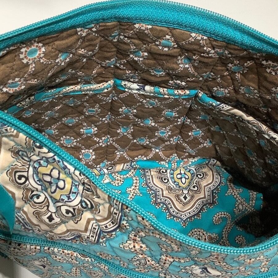 An open bag with teal, brown, and beige paisley-patterned fabric interior, showing detailed stitching and a zipped compartment. No landmarks or historical buildings visible.