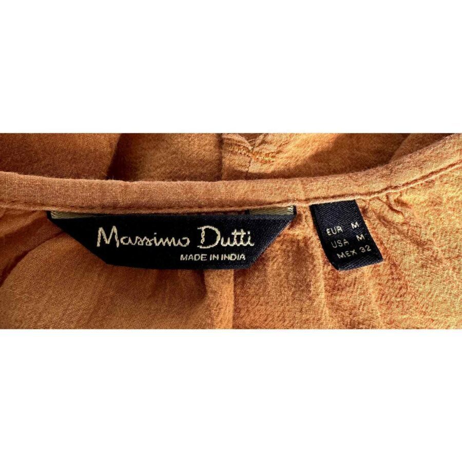 A close-up view of a Massimo Dutti clothing label, indicating the garment is made in India and available in size M for various regions.