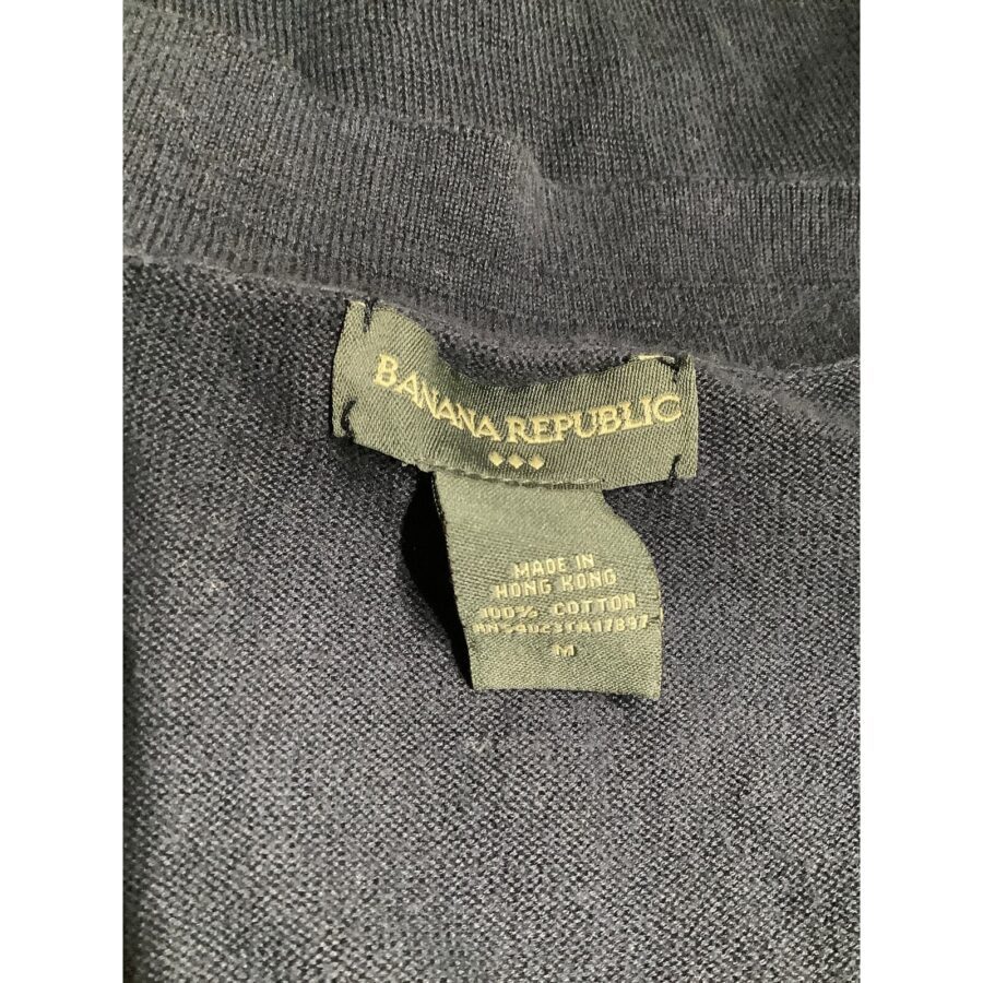 A clothing label from Banana Republic, indicating the garment is made in Hong Kong from 100% cotton, displayed against a dark fabric background.