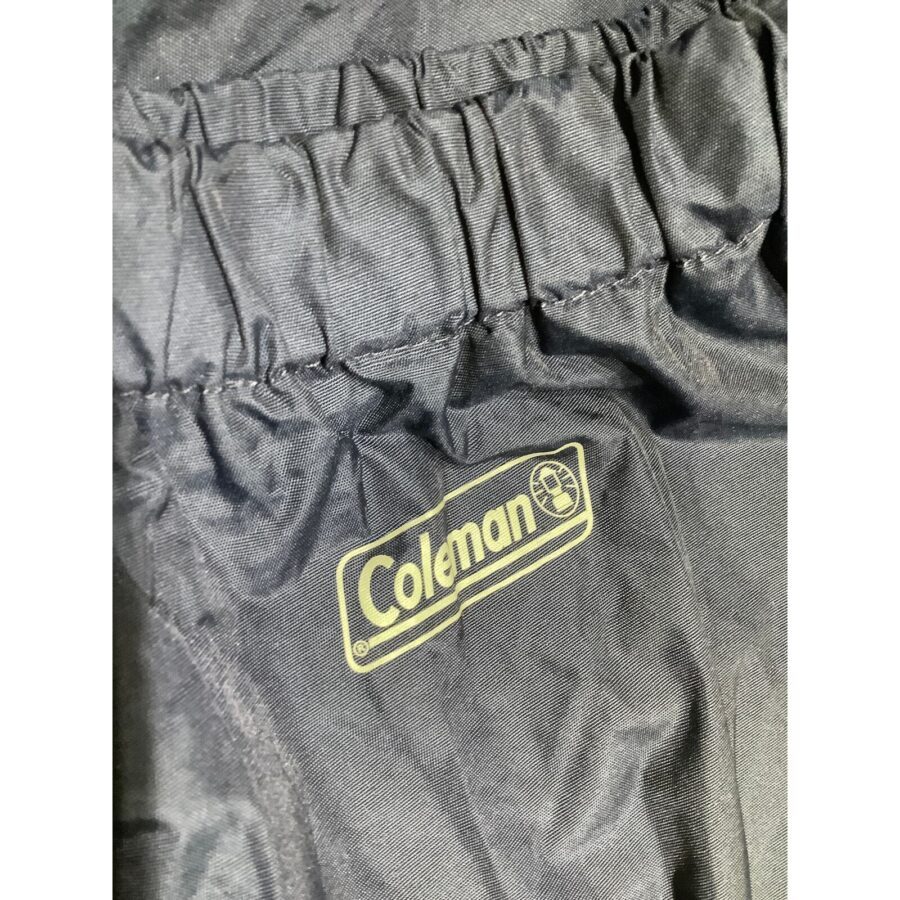 The image shows a close-up view of black fabric with the "Coleman" logo stitched onto it, likely part of outdoor or camping gear.