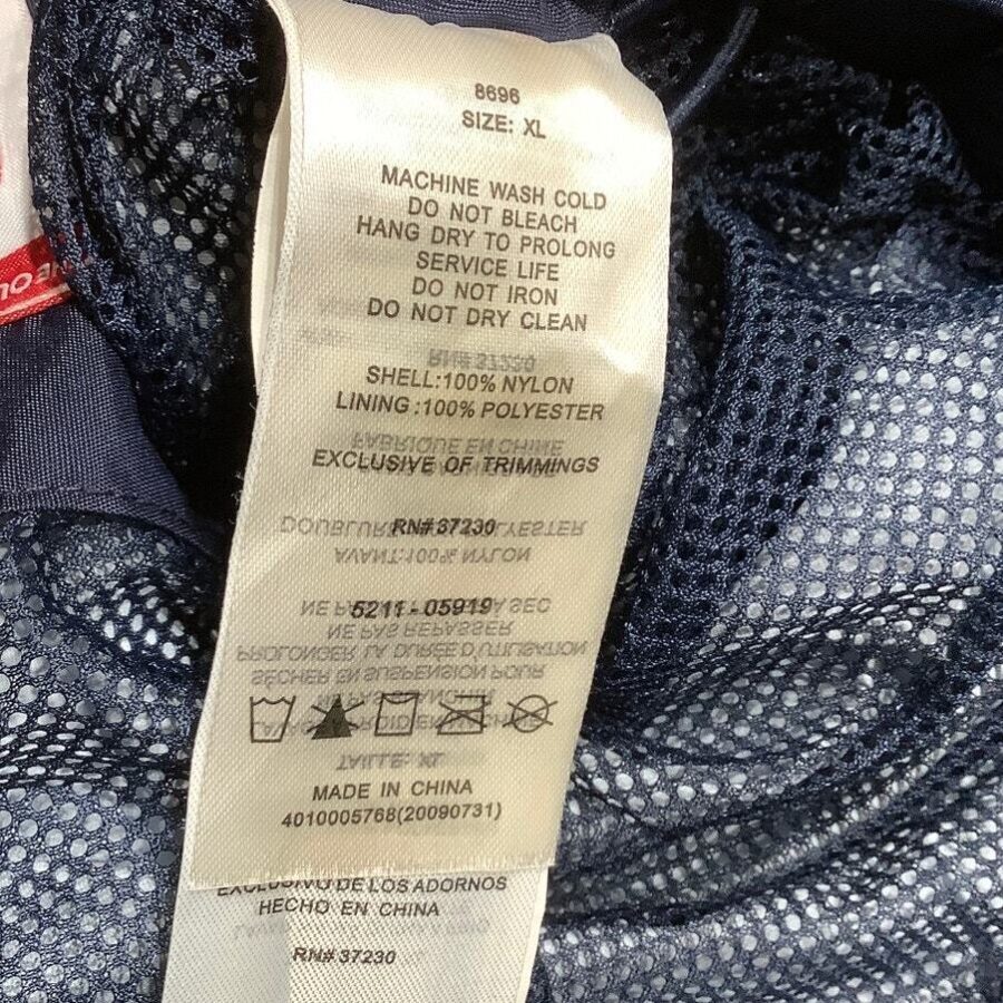 A clothing label with care instructions and fabric details is attached to a navy blue mesh garment. Size: XL. Made in China.