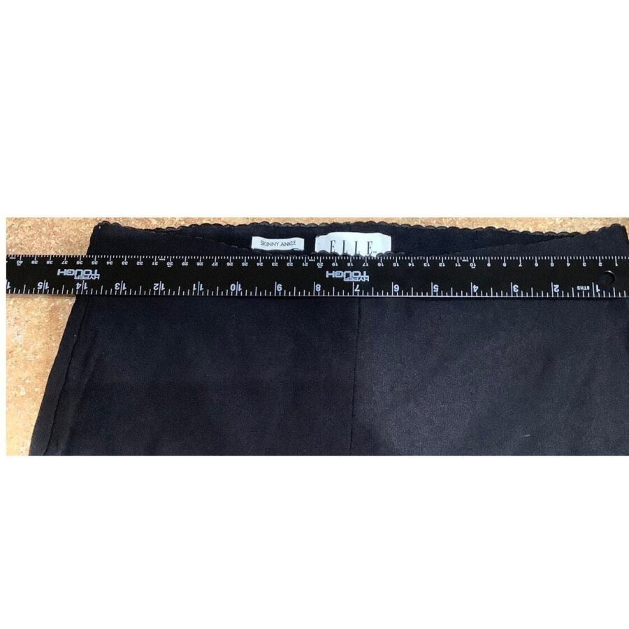 A black Elle garment measured by a ruler, showing a waist width of approximately 13 inches. Labels indicate brand and material details.