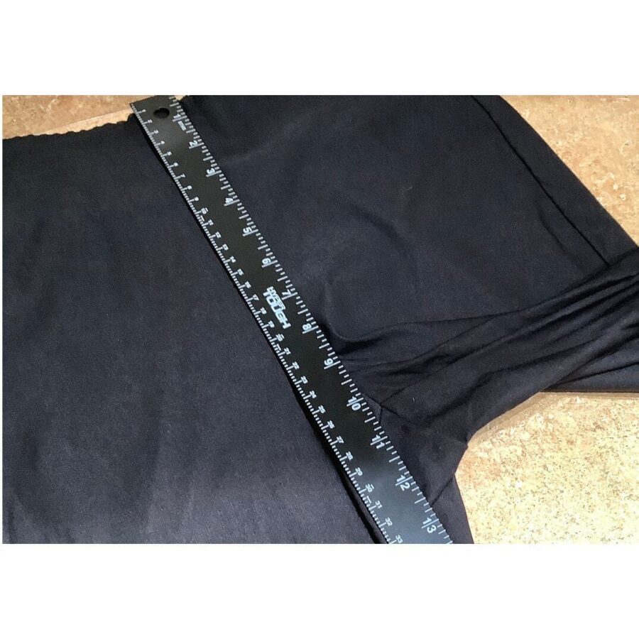 A black piece of fabric is being measured with a black ruler placed diagonally across it, showing the measurement marks clearly.