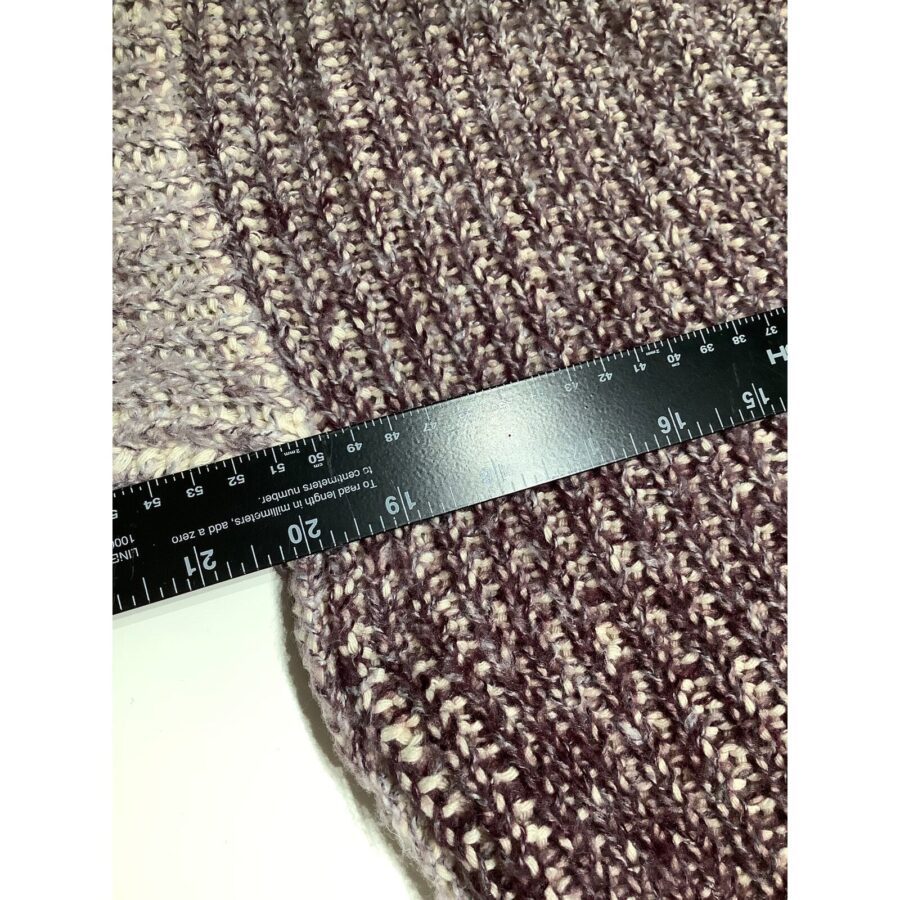 A close-up of a ruler placed on a knitted fabric with a textured pattern, capturing measurements in inches and centimeters.