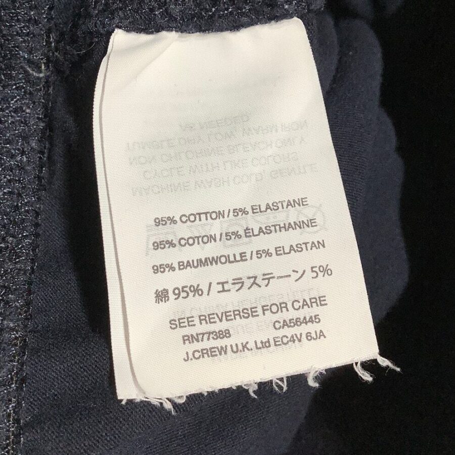 A clothing label displaying fabric composition: 95% cotton and 5% elastane, along with care instructions and company information for J.Crew U.K. Ltd.