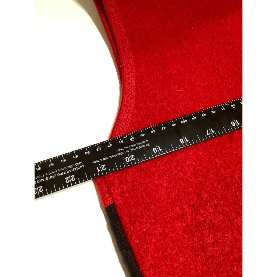 A black ruler marked in inches and centimeters is placed on a piece of red fabric. The background is white.