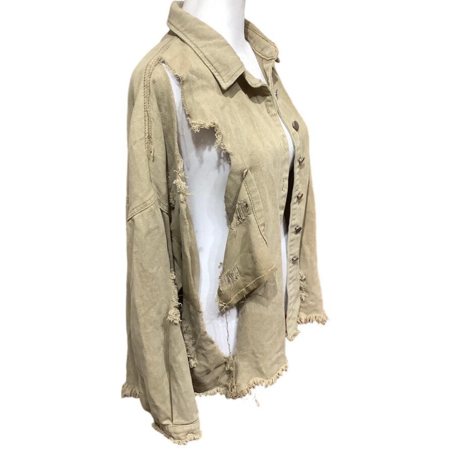 A beige, distressed jacket displayed on a white mannequin. The jacket features several large tears and frayed edges, highlighting a rugged and worn style.