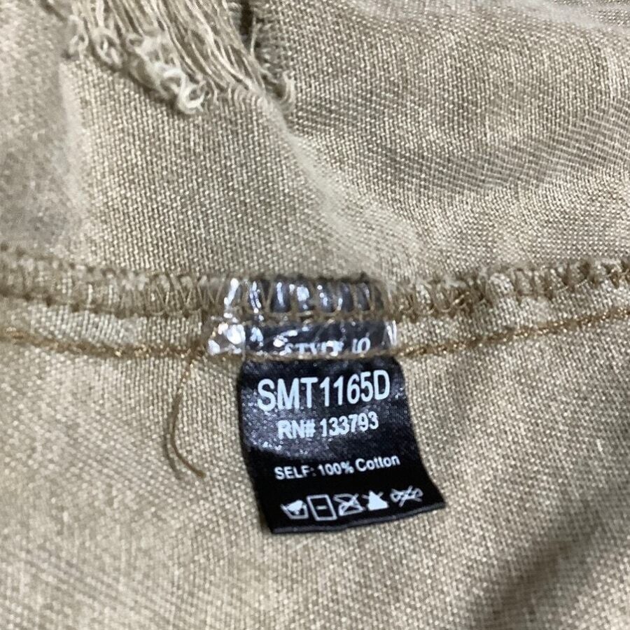 A close-up image of a beige fabric tag displaying washing instructions and material information, indicating it's 100% cotton with identifiers SMT1165D and RN# 133793.