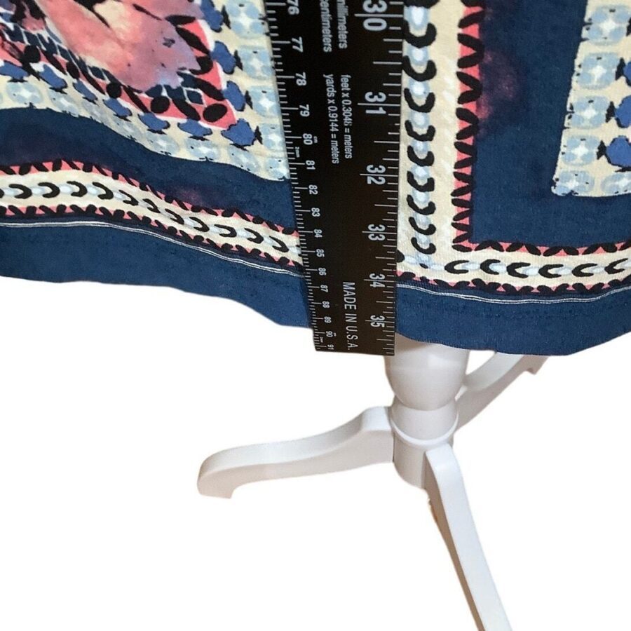 A patterned garment is being measured with a ruler to check its length, placed on a white stand. The ruler reads "MADE IN U.S.A.".