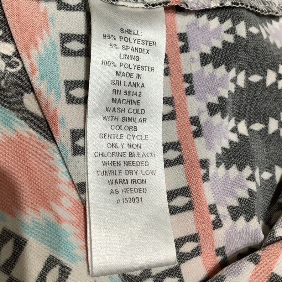 A clothing tag showing material composition and care instructions, including washing details, made in Sri Lanka, attached to a patterned fabric with geometric shapes.