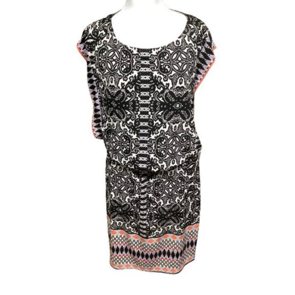 Black-and-white patterned dress with short sleeves and coral accents along the edges, displayed on a mannequin, featuring an intricate, symmetric design.