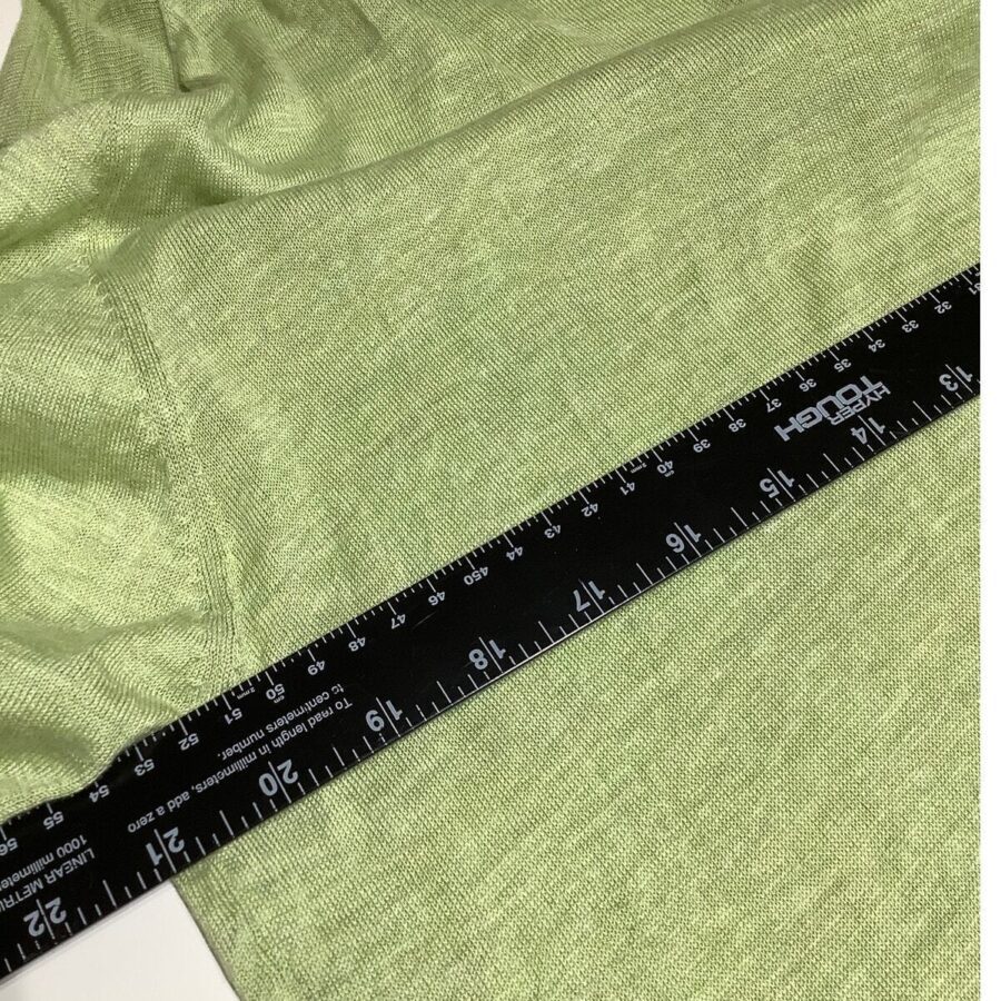 A black measurement ruler is placed on a green fabric. The fabric appears soft and textured, with the ruler indicating measurement in inches and centimeters.