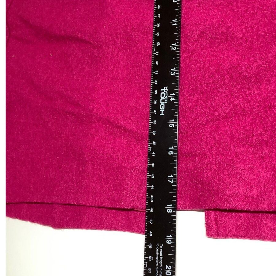 A close-up image of a ruler measuring a red fabric. The ruler displays both inches and centimeters, highlighting a measurement of approximately 15 inches.