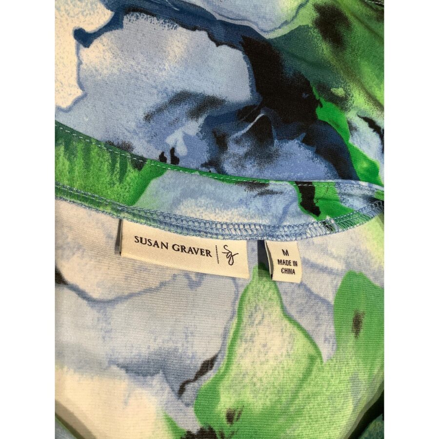 A close-up of a colorful fabric with a label reading "Susan Graver, M, Made in China." The fabric features blue and green patterns.