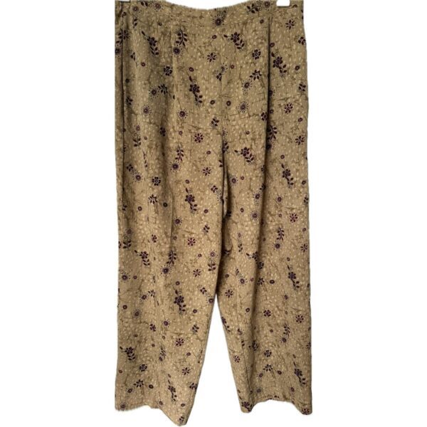 The image shows a pair of beige pants with a floral pattern, featuring small purple flowers. The fabric appears soft and comfortable.