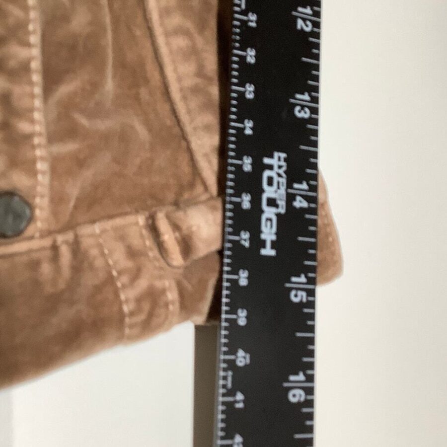 A close-up image of a brown jacket with a black ruler placed vertically beside it, showing measurements in inches and centimeters.