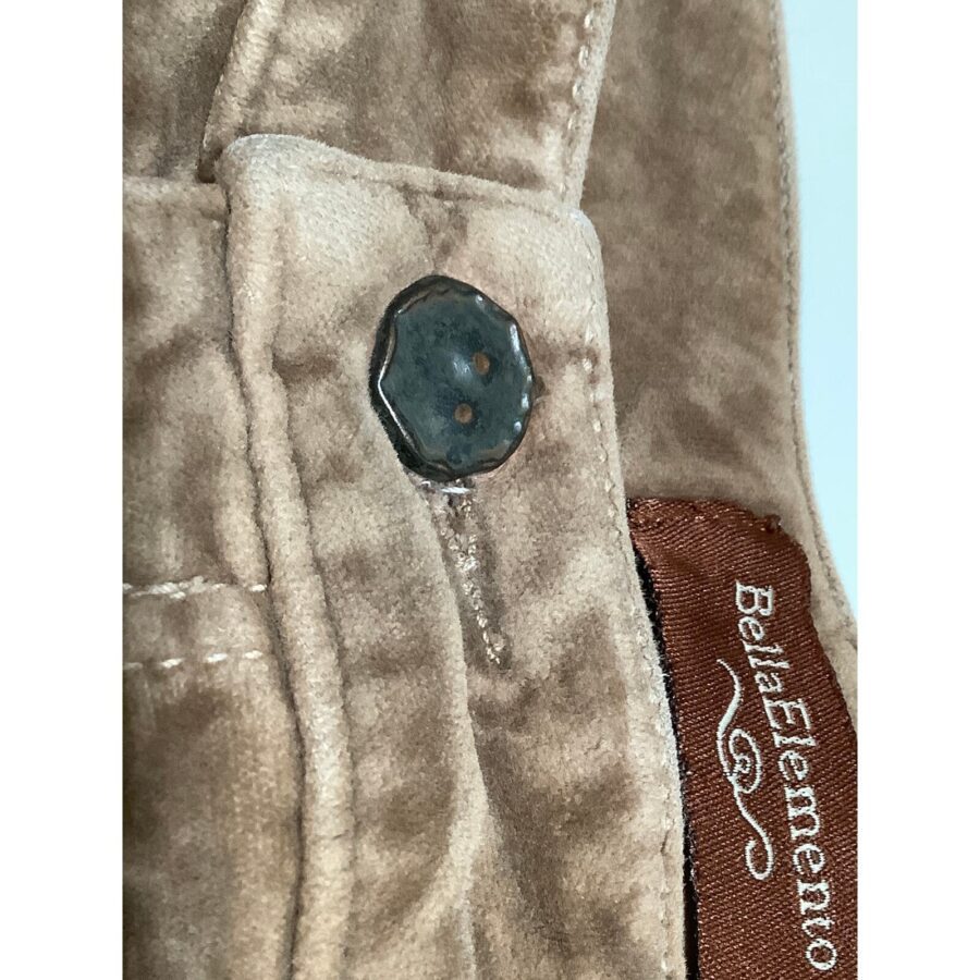 Close-up of a beige fabric button and buttonhole. The edge of a brown label with the text "BellaElemento" is visible on the garment.