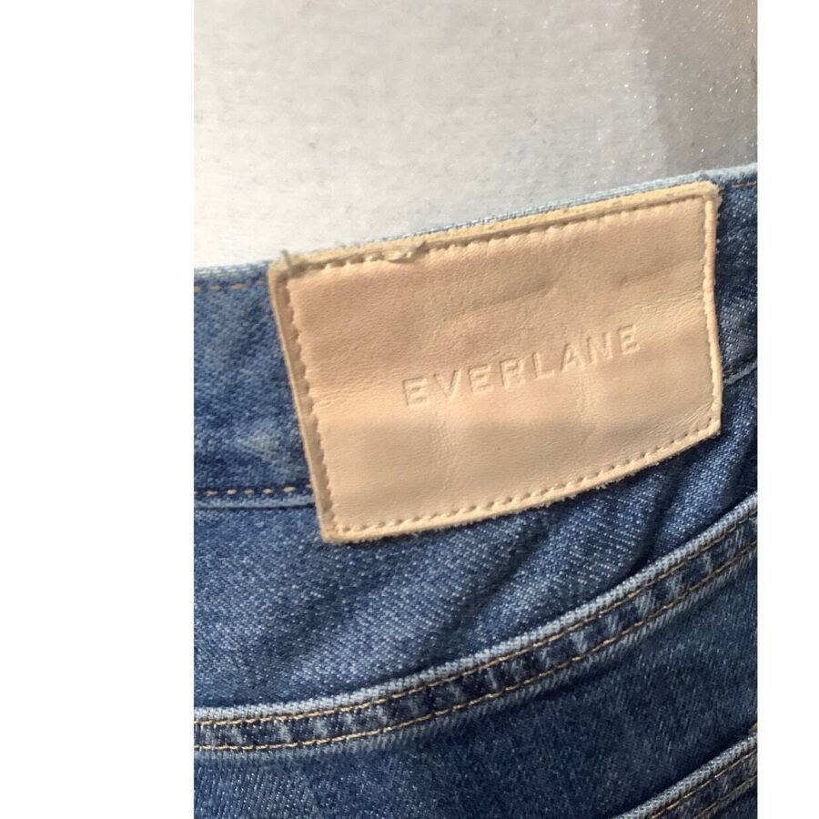 Close-up of a denim waistband displaying an Everlane leather patch. No recognizable landmarks or historical buildings are present.