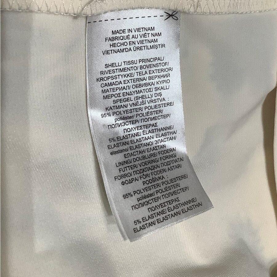 A close-up of a garment label outlines the material composition and care instructions, indicating the item is made in Vietnam and composed mostly of polyester.