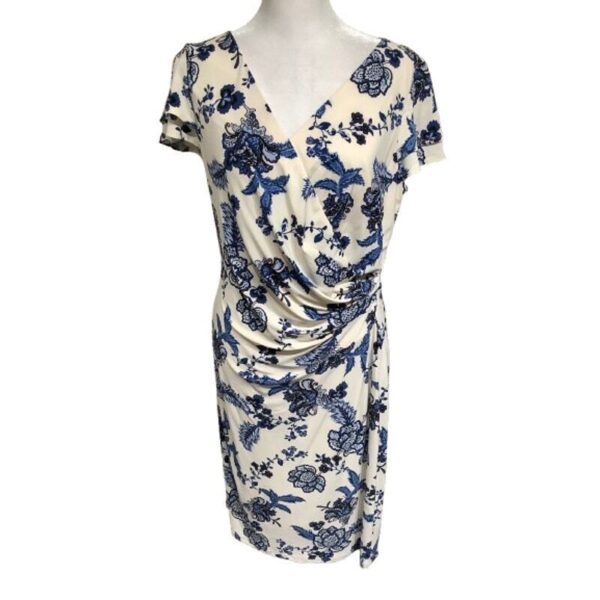 A white floral dress with blue patterns displayed on a mannequin, featuring short sleeves and a V-neckline with a ruched waist design.