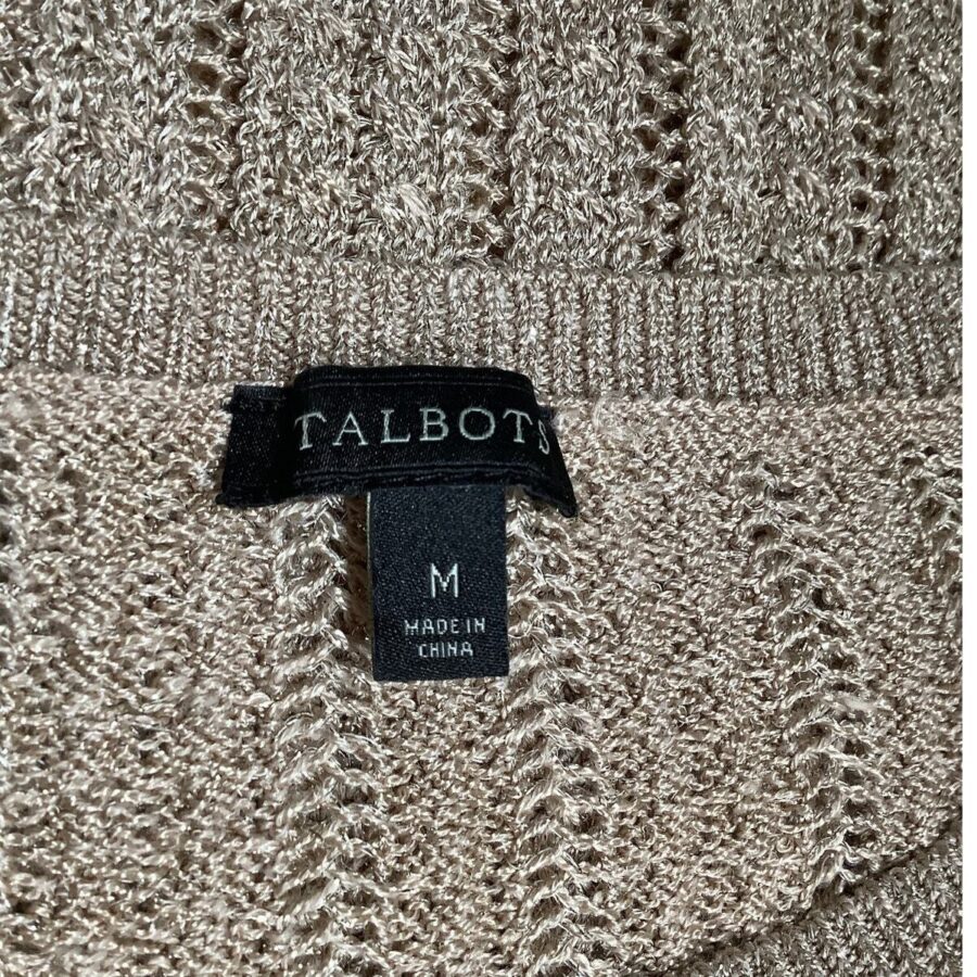 A close-up of a beige knit garment with a "Talbots" label showing size "M" and "Made in China." No landmarks or historical buildings visible.