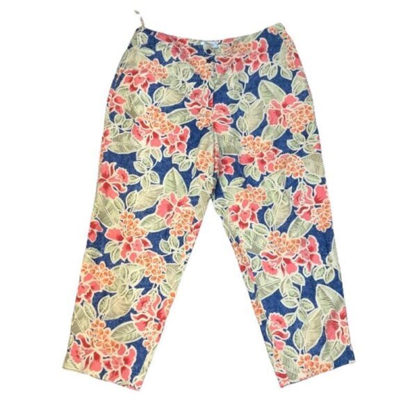 A pair of vibrant, floral-printed pants featuring red flowers and green leaves on a blue background, laid out against a plain white backdrop.