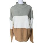 A color-blocked sweater displayed on a mannequin with three sections: grey, white, and beige, featuring a textured knit design and a high neckline.