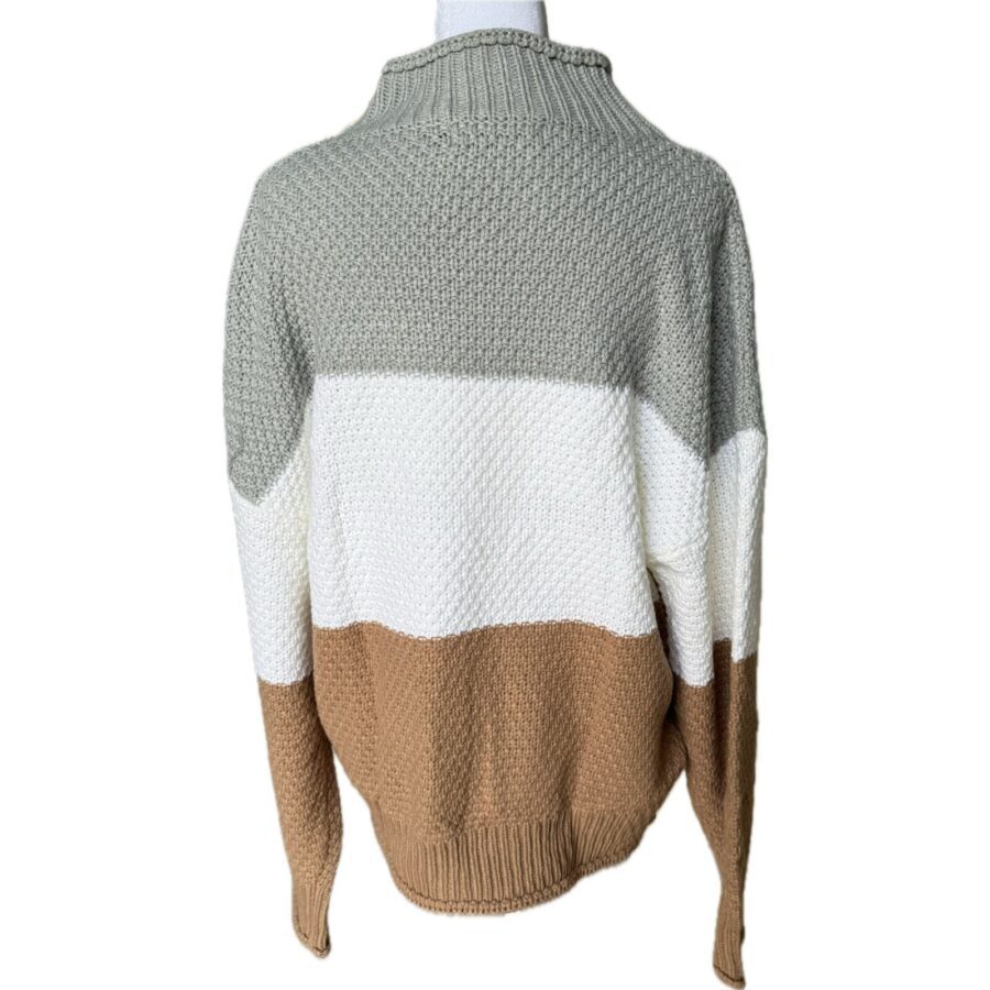 A knitted, tri-color sweater in shades of grey, white, and brown displayed on a mannequin, showing a textured pattern and cozy design.