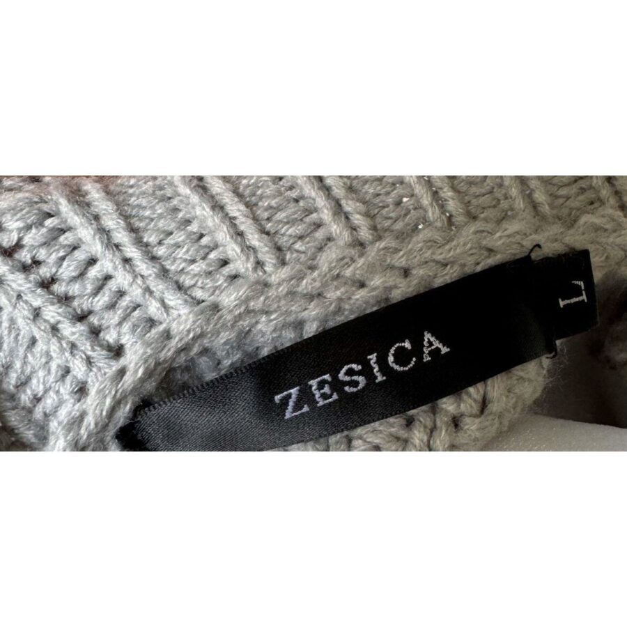 A close-up of a gray knitted fabric with a black label reading "ZESICA L" attached to it, indicating the size.