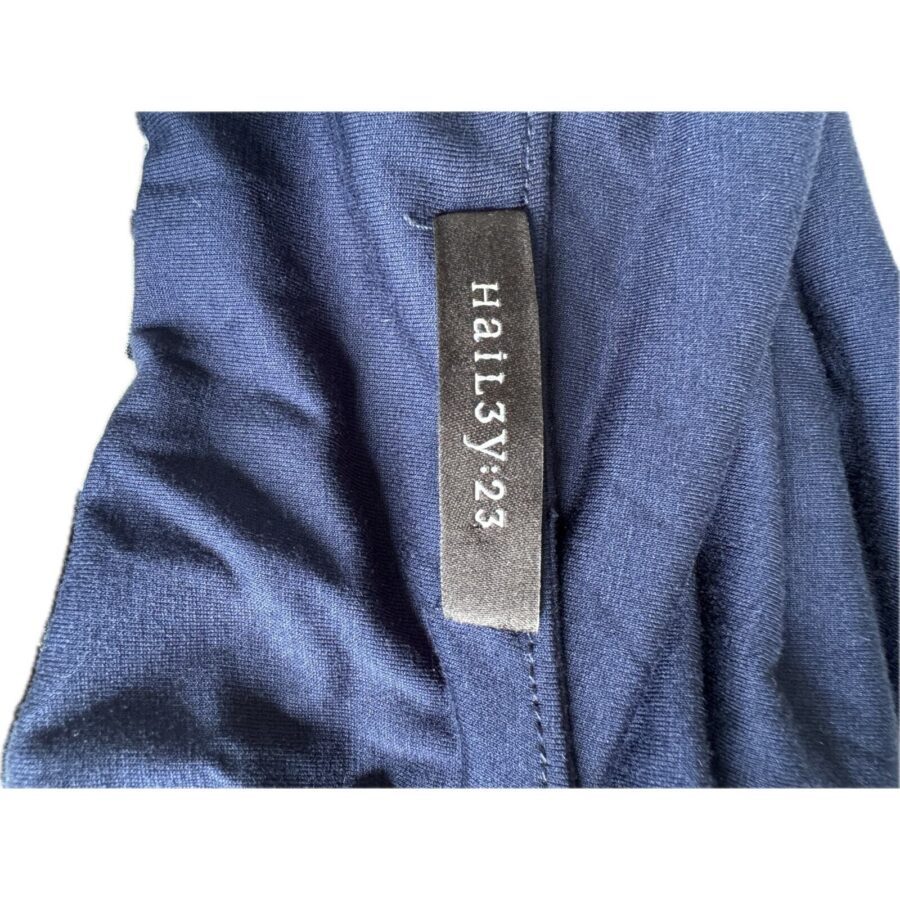 A close-up of a blue fabric garment with a black label that reads "Halit3y23." The fabric appears soft and slightly textured.