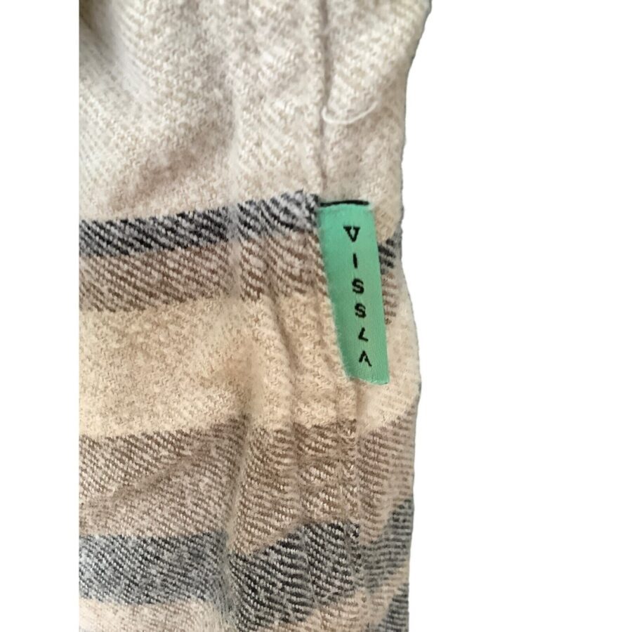 Close-up of a fabric with beige and gray stripes, featuring a small green tag labeled "VISSLA" in black letters.