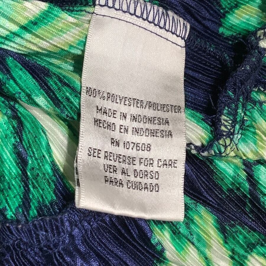 A close-up image of a clothing tag on a colorful fabric. The tag indicates the garment is made of 100% polyester and manufactured in Indonesia.