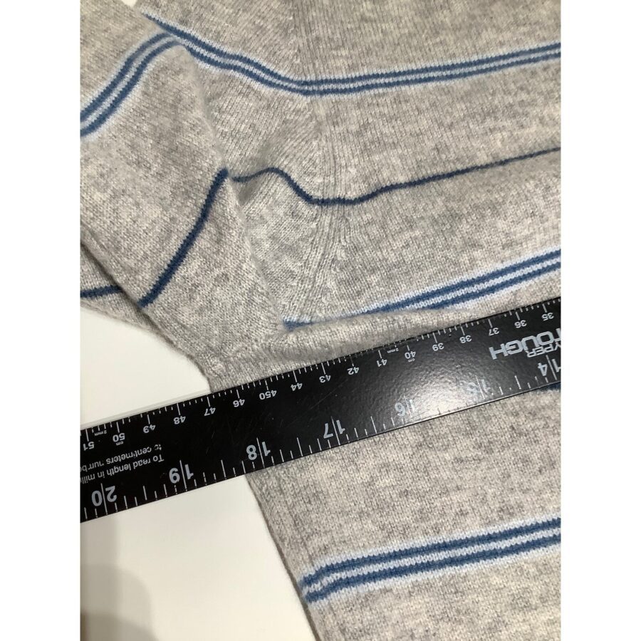 A close-up of a gray fabric with blue stripes and a ruler measuring 12 inches placed on it, against a white background.