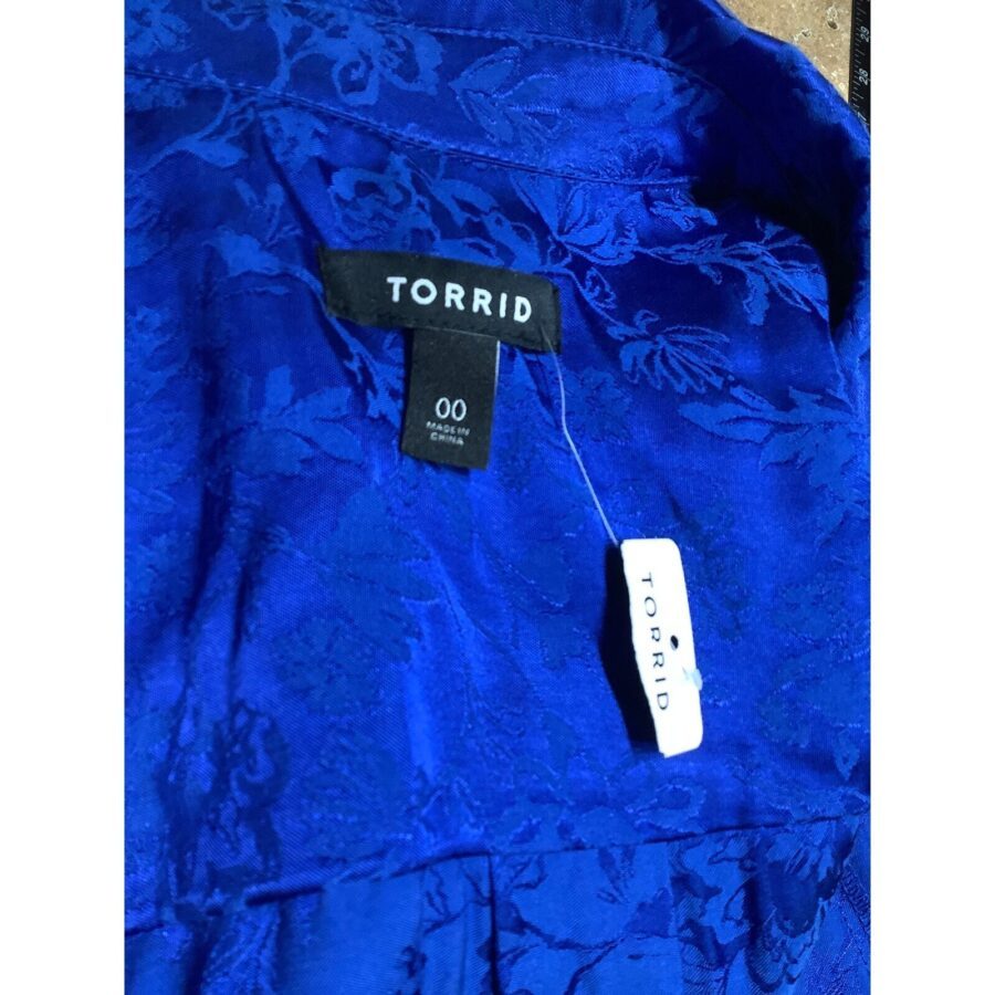 A close-up of a blue fabric with floral patterns. Contains a label reading "TORRID 00" and a price tag attached. No landmarks visible.