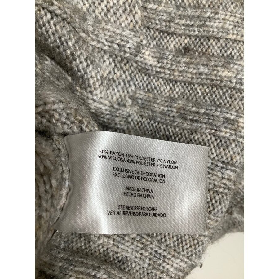 A close-up of a gray knitted fabric with a care label indicating the materials used and care instructions in English and Spanish.