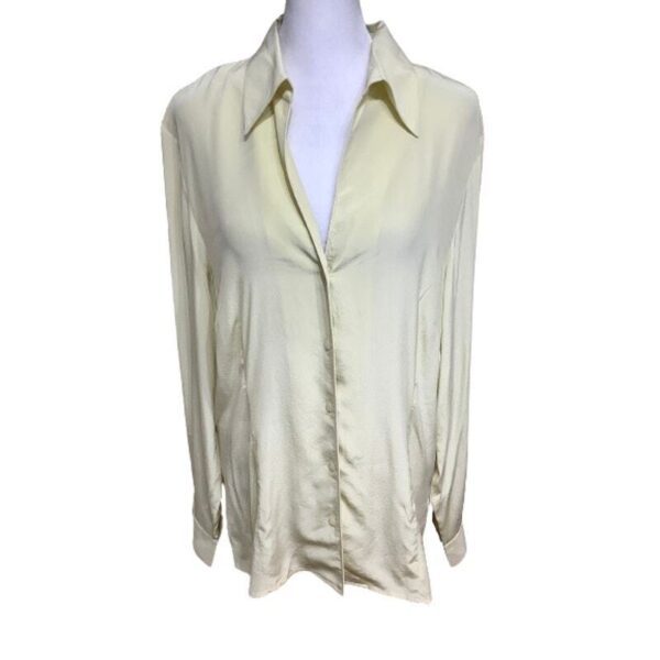 A light yellow, long-sleeve blouse is displayed on a white mannequin torso, featuring a collared neckline and button-up front.