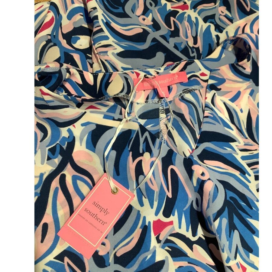 A colorful shirt with a blue, pink, and white abstract pattern, featuring a "Simply Southern" tag attached to the collar.